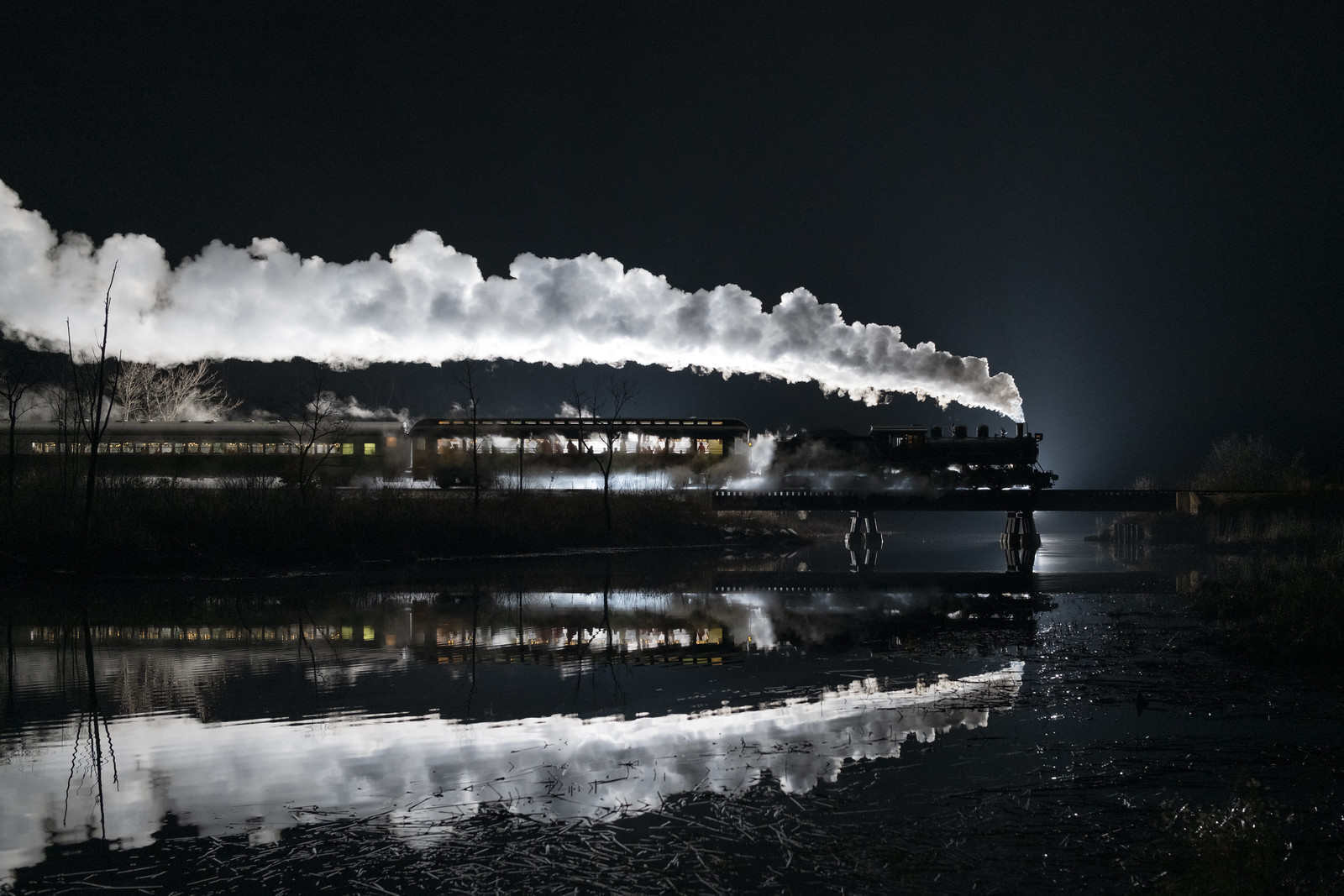 Steam train at night its with exhaust illuminated overhead